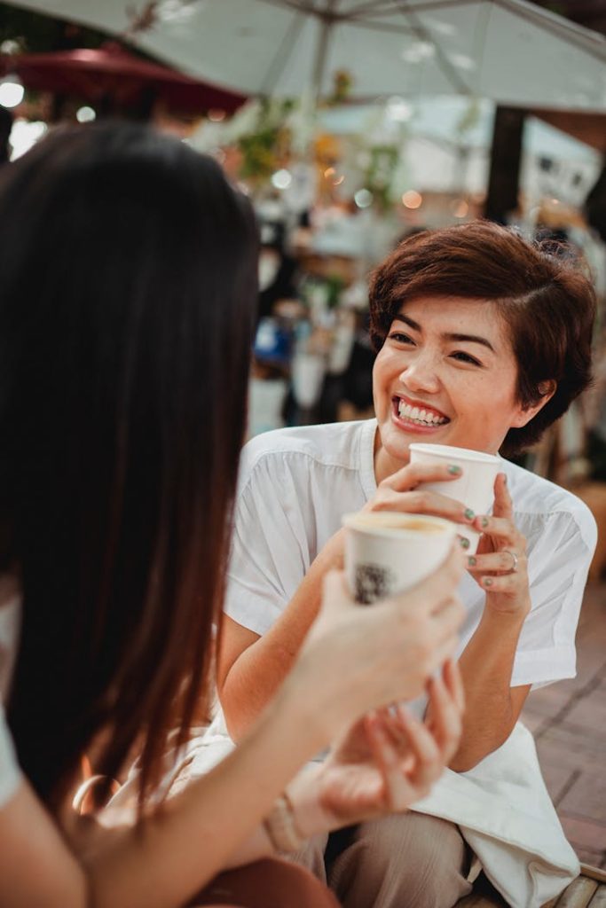 Mastering the First Impression: Your intriguing post title goes here Two women enjoying a joyful coffee conversation outdoors at a café